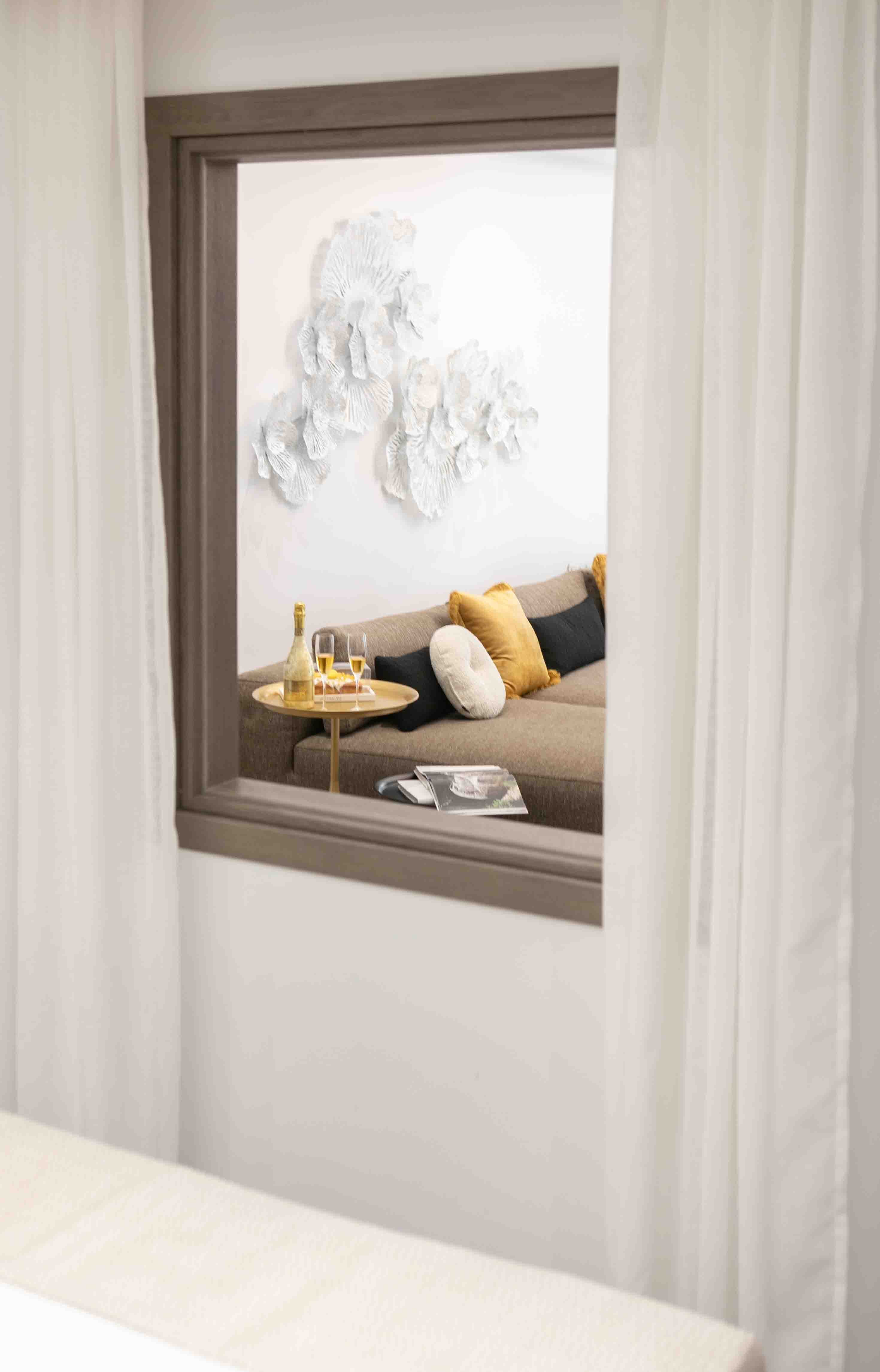 a window with a table and a chair with a pillow and a tray of food on it