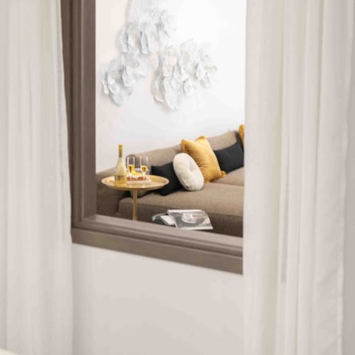 a window with a table and a chair with a pillow and a tray of food on it