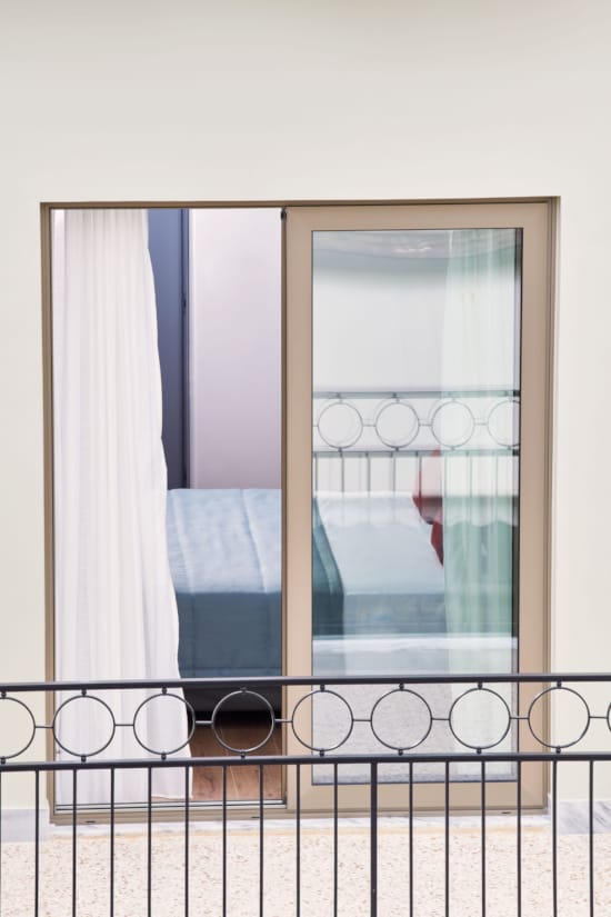 a window with a railing and a bed in the background