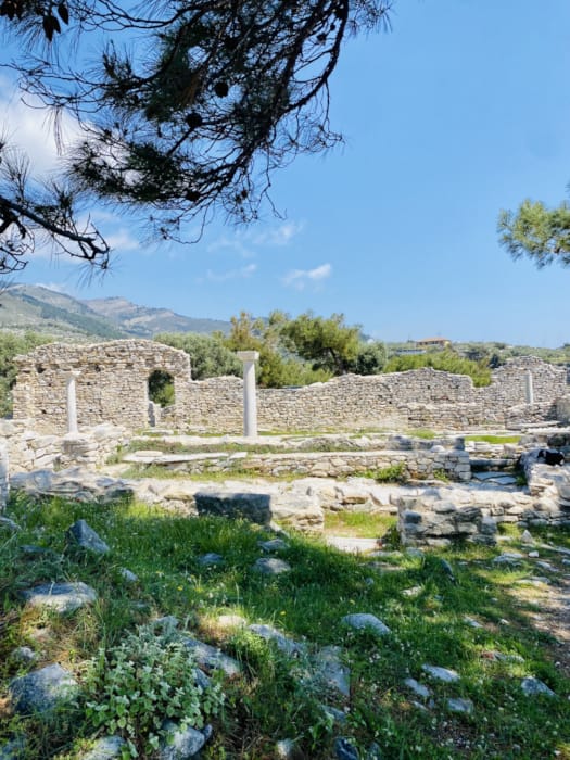 a stone wall with columns and a stone structure in the background