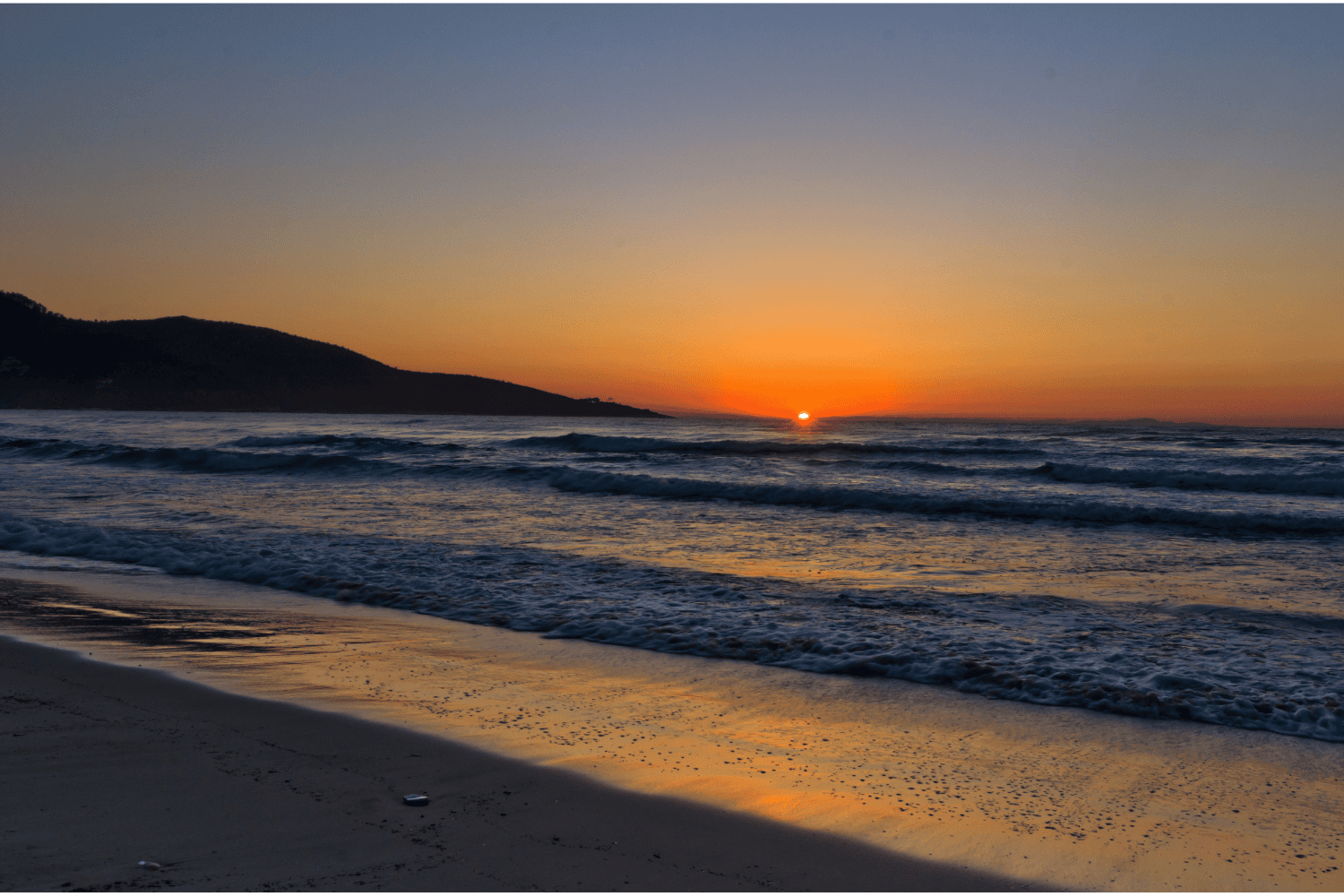 a beach with waves and a sunset