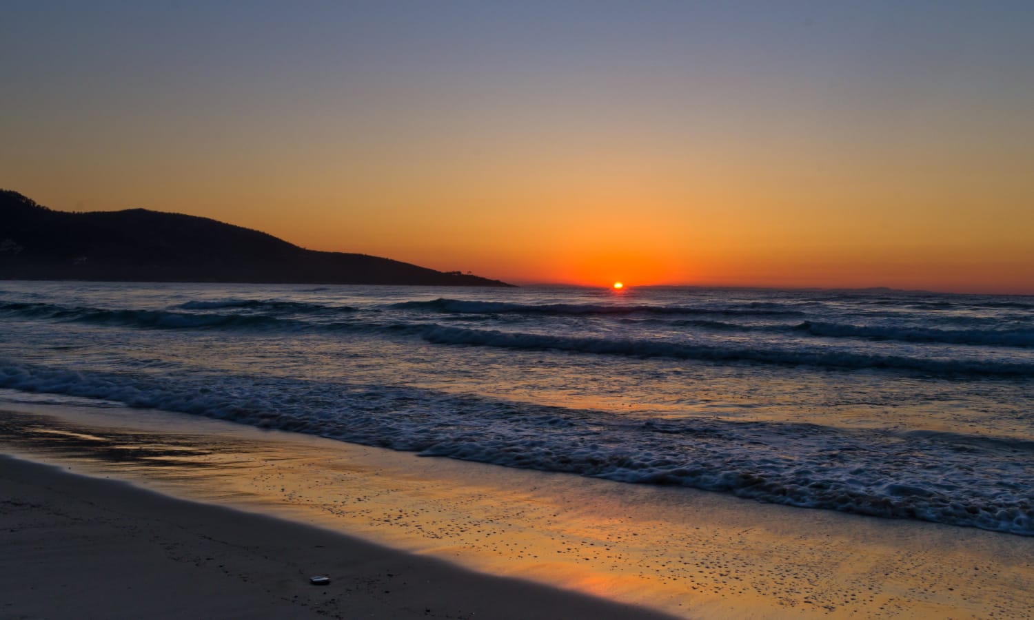 a beach with waves and a sunset