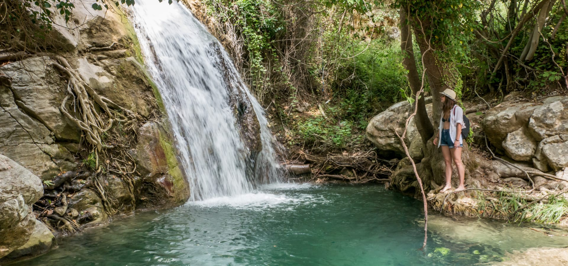 a man standing on a log over a river with a waterfall