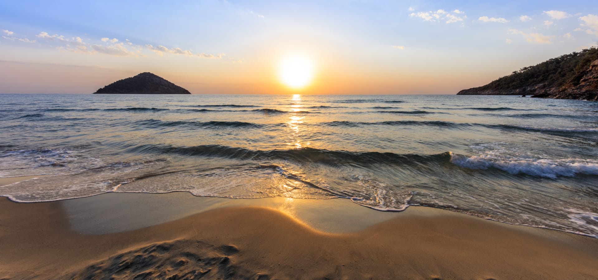 a beach with waves and the sun setting