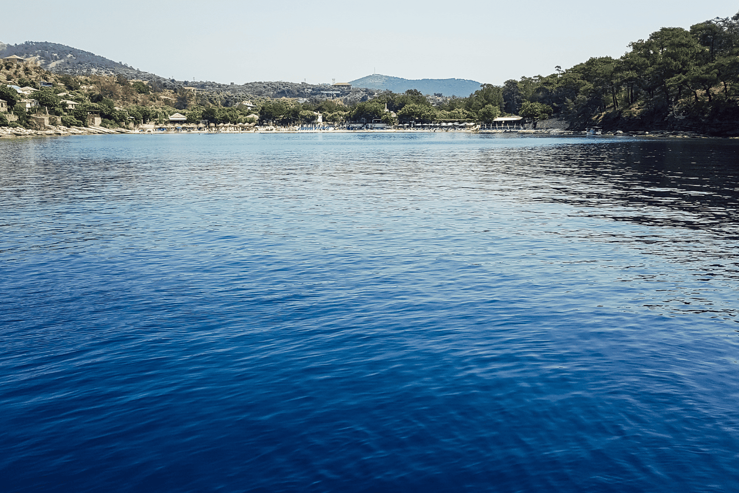 a body of water with trees and hills in the background