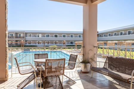 a deck with chairs and tables by a body of water