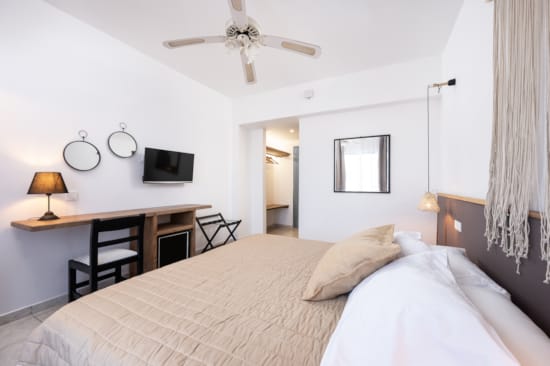 a bedroom with a bed desk and a fan