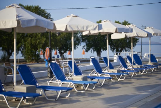 a group of blue chairs sit under umbrellas