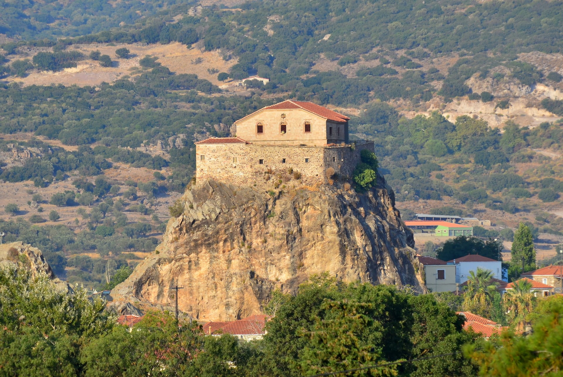 a large building on a cliff with Meteora in the background