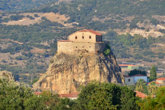 a large building on a cliff with Meteora in the background