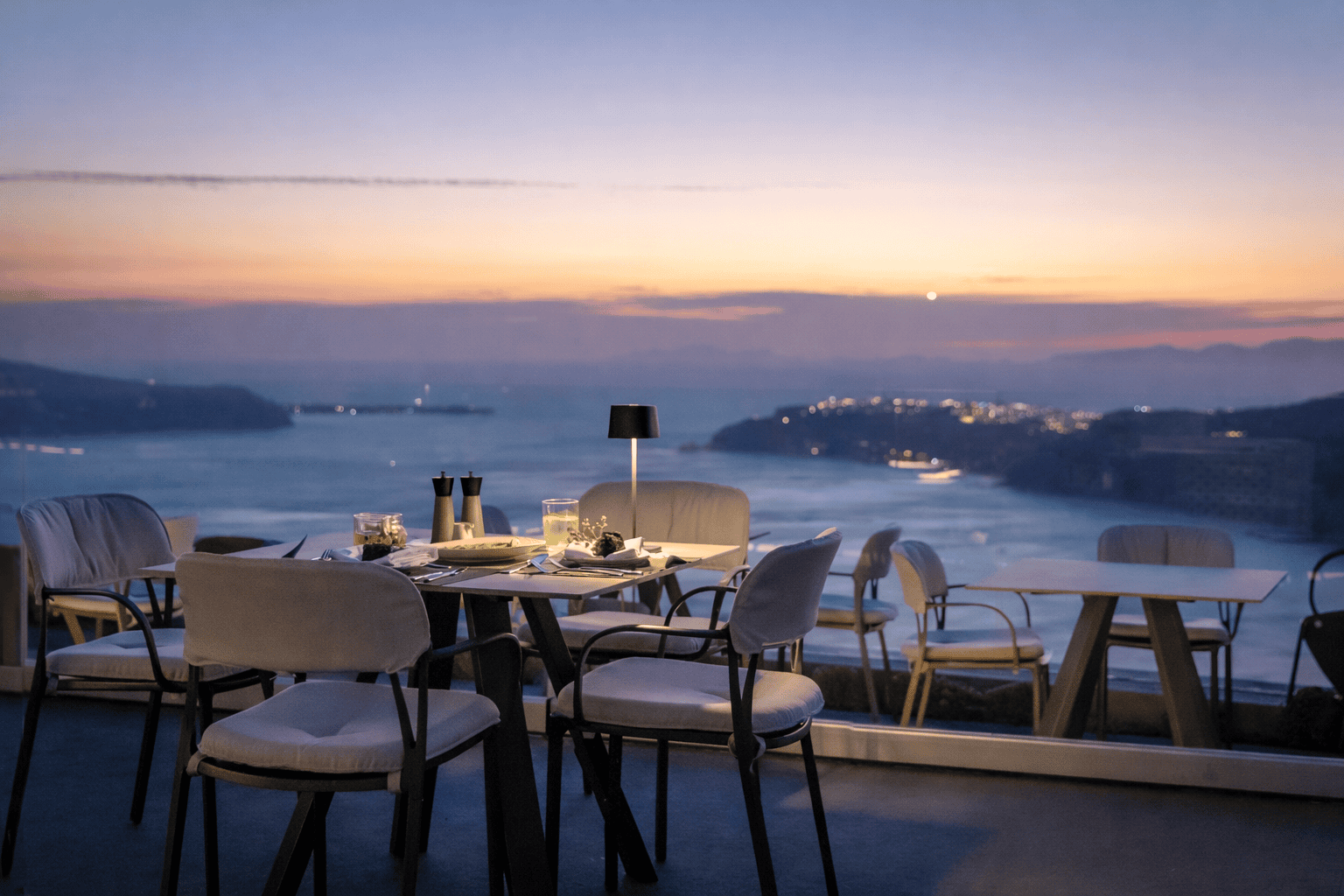 a group of tables and chairs on a deck overlooking a body of water