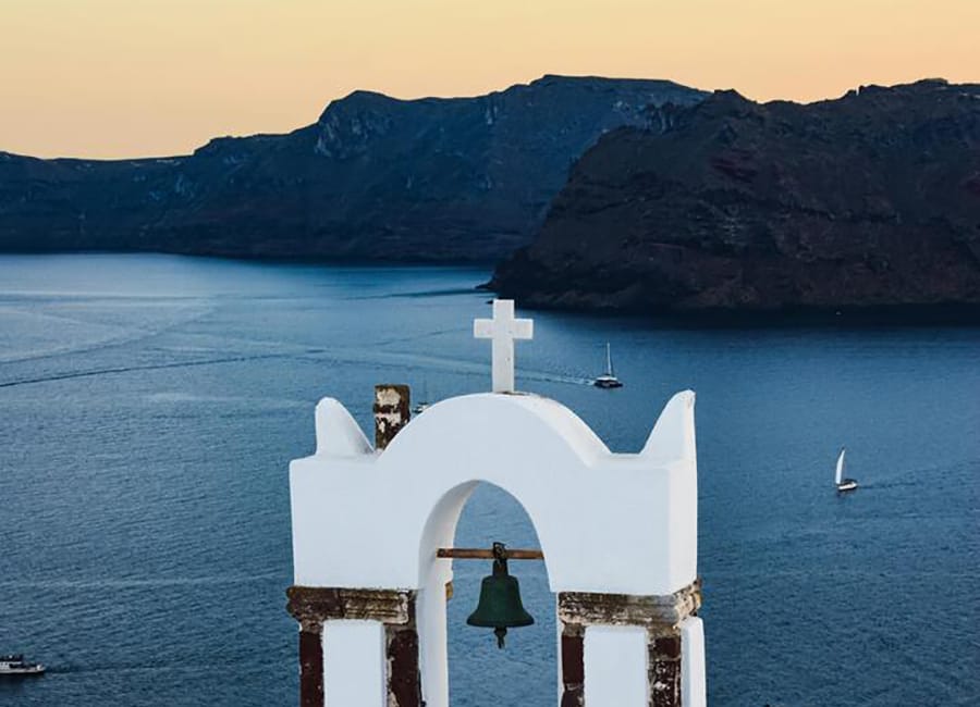 a white building with a cross on top of it surrounded by water