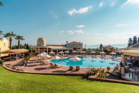 a pool with umbrellas and chairs in front of a building