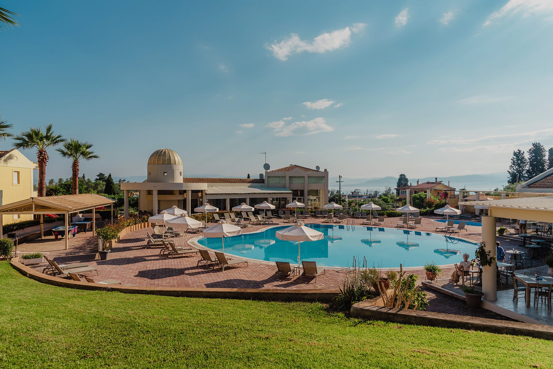 a pool with umbrellas and chairs in front of a building