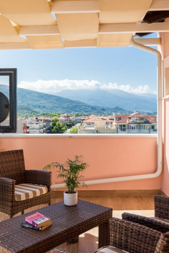 a room with a table and chairs and a window with a view of a town and mountains