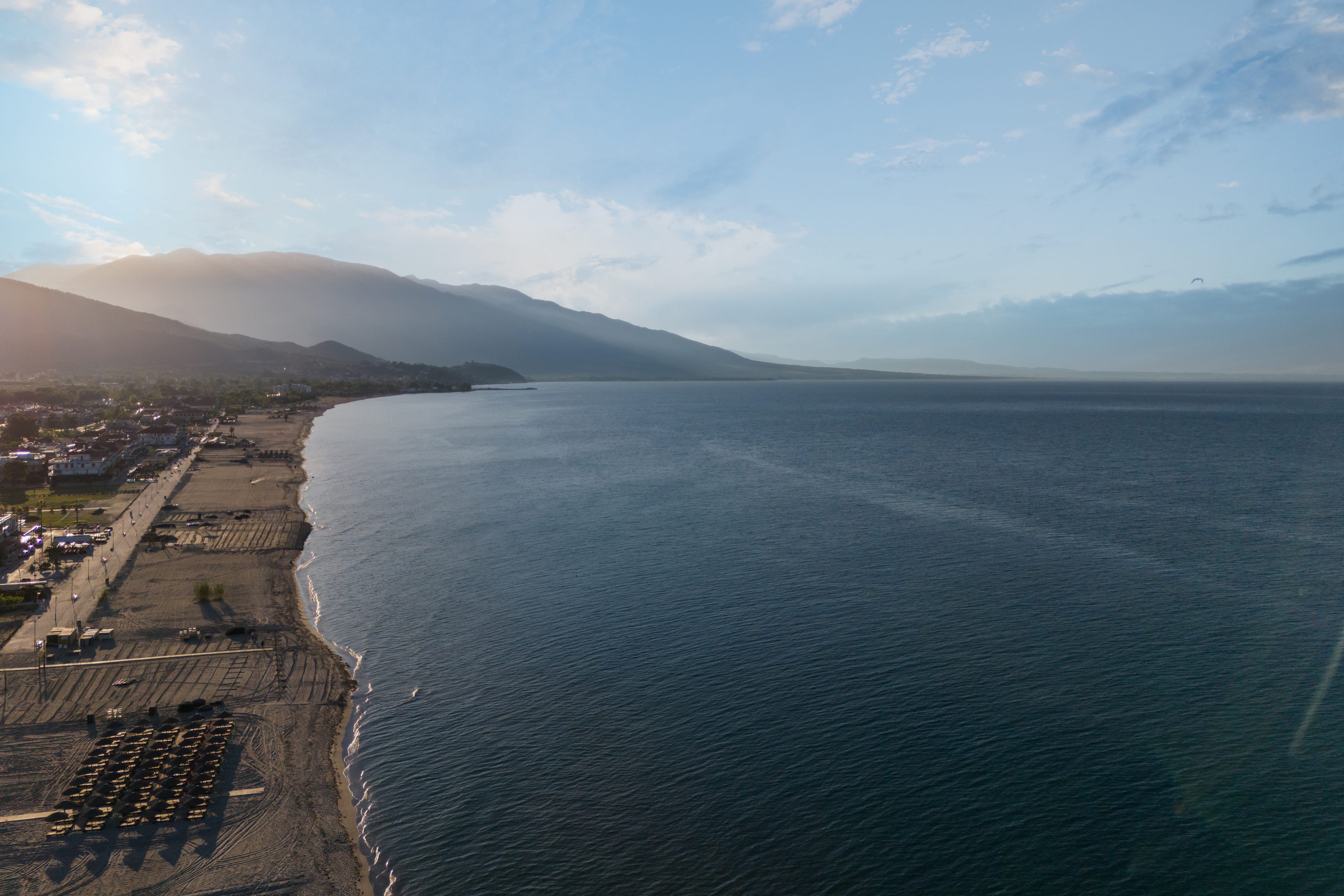 a body of water with a beach and mountains in the background
