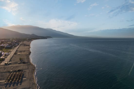 a body of water with a beach and mountains in the background