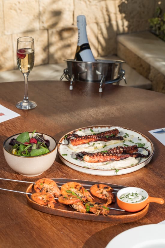 a table with plates of food and a glass of wine