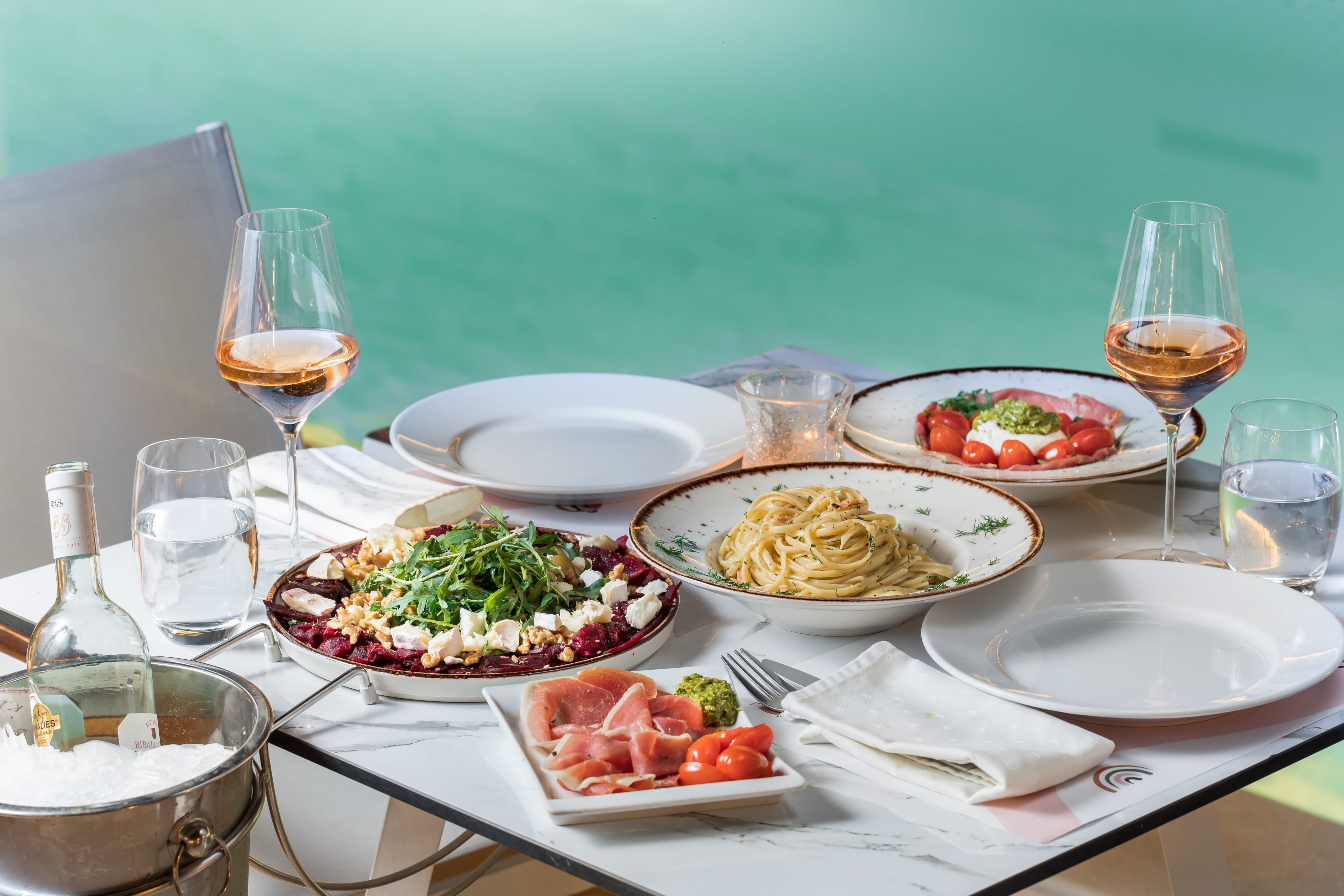 a table with plates of food and glasses of wine