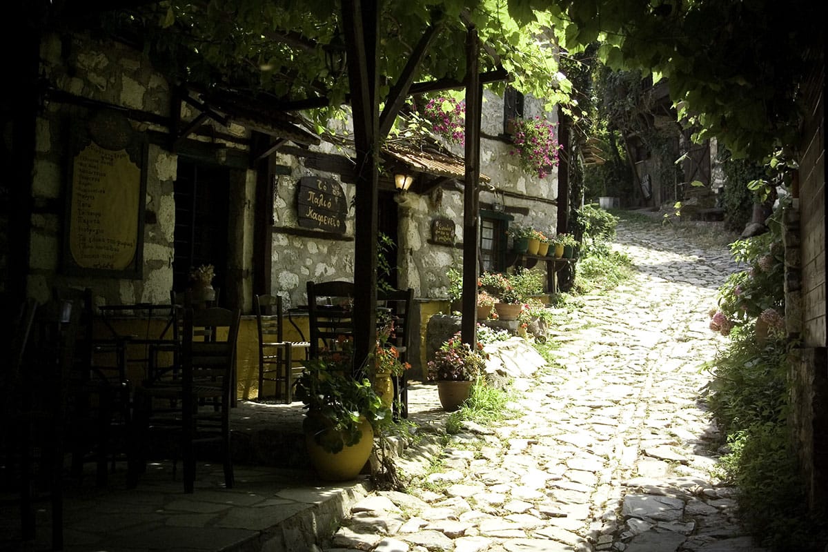 a path with chairs and plants on it next to a building