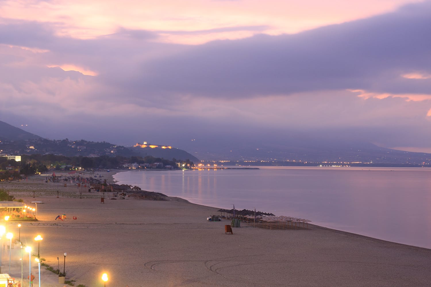 a beach with a body of water and a city in the distance
