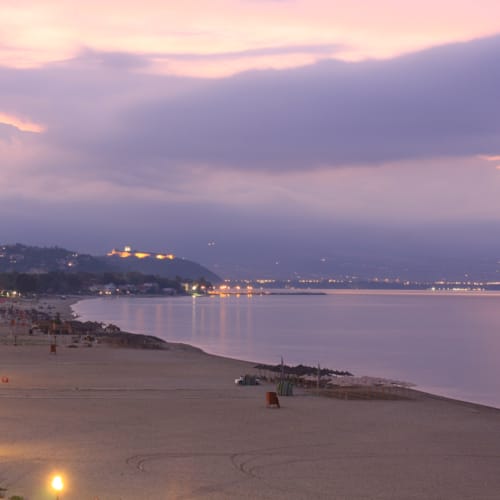 a beach with a body of water and a city in the distance