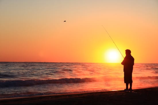 a man fishing at sunset