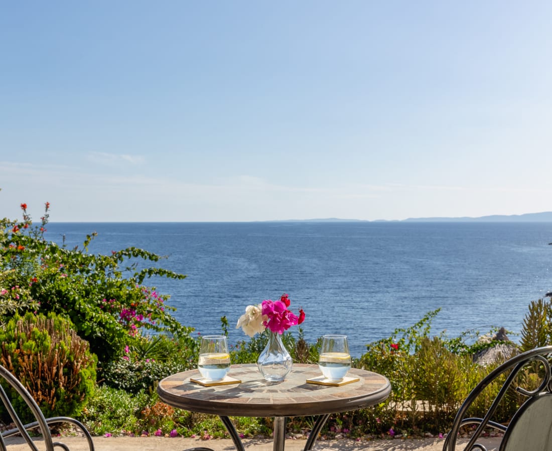 a table with a vase of flowers on it by a body of water