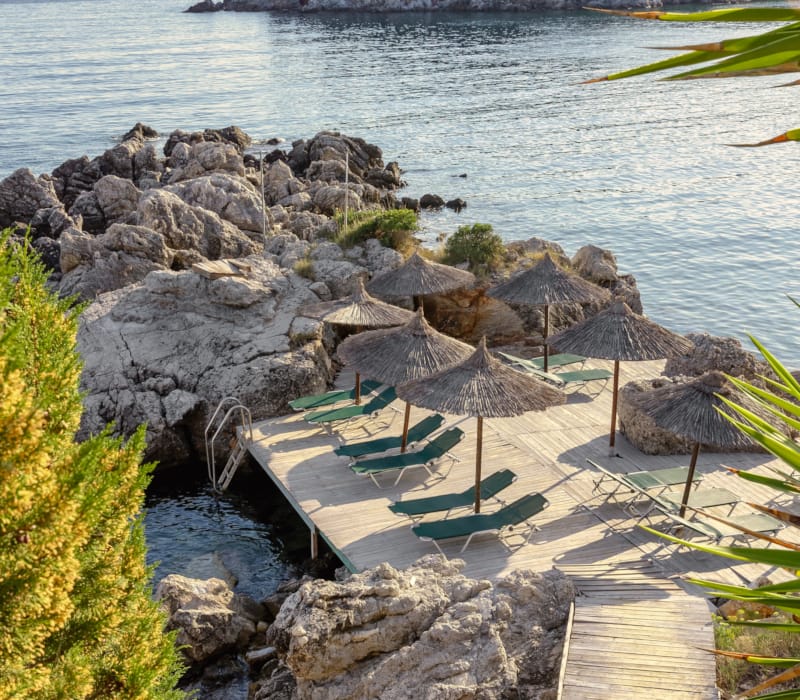 a deck with umbrellas and a body of water in the background