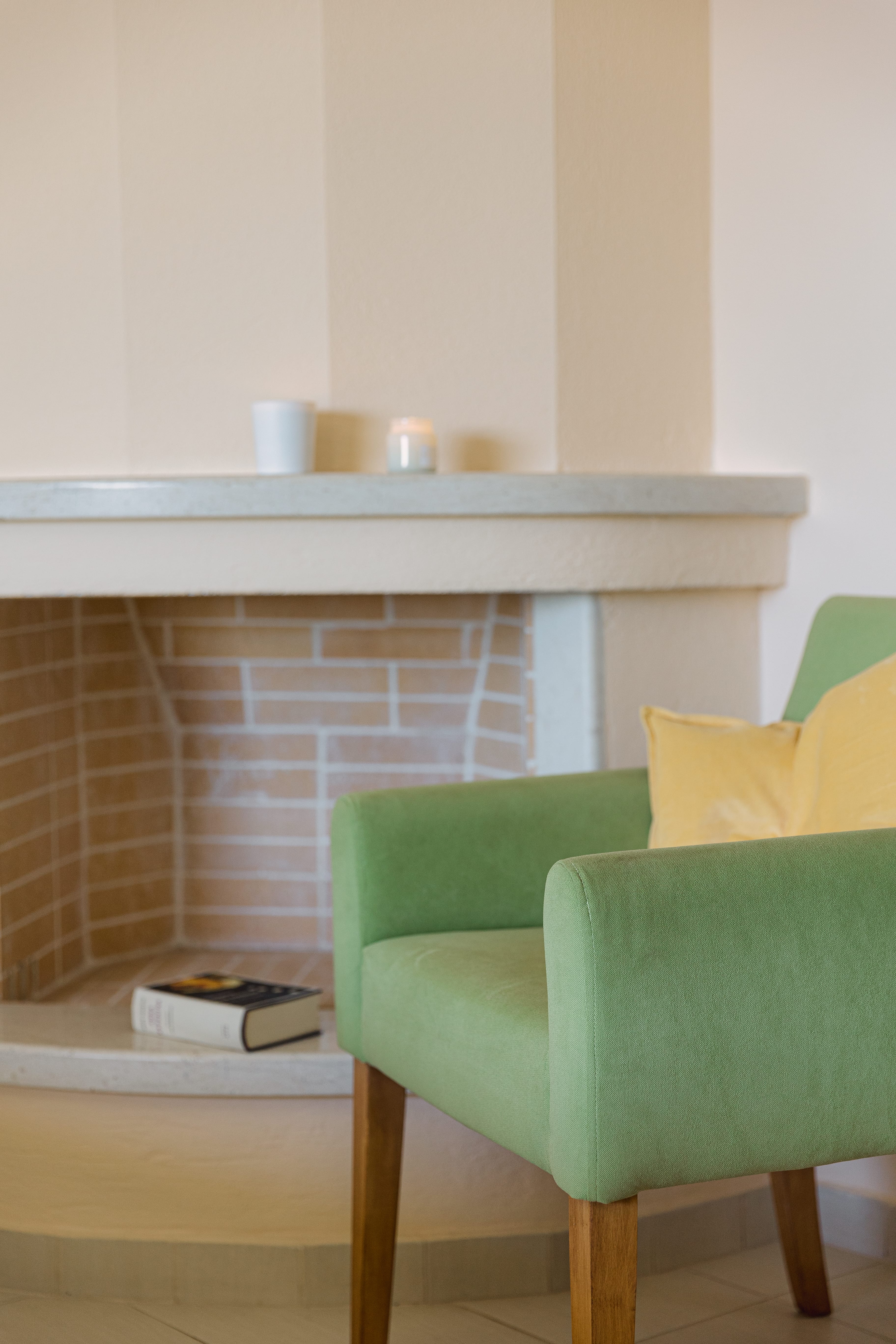 a table with a chair and a green chair in front of a brick wall