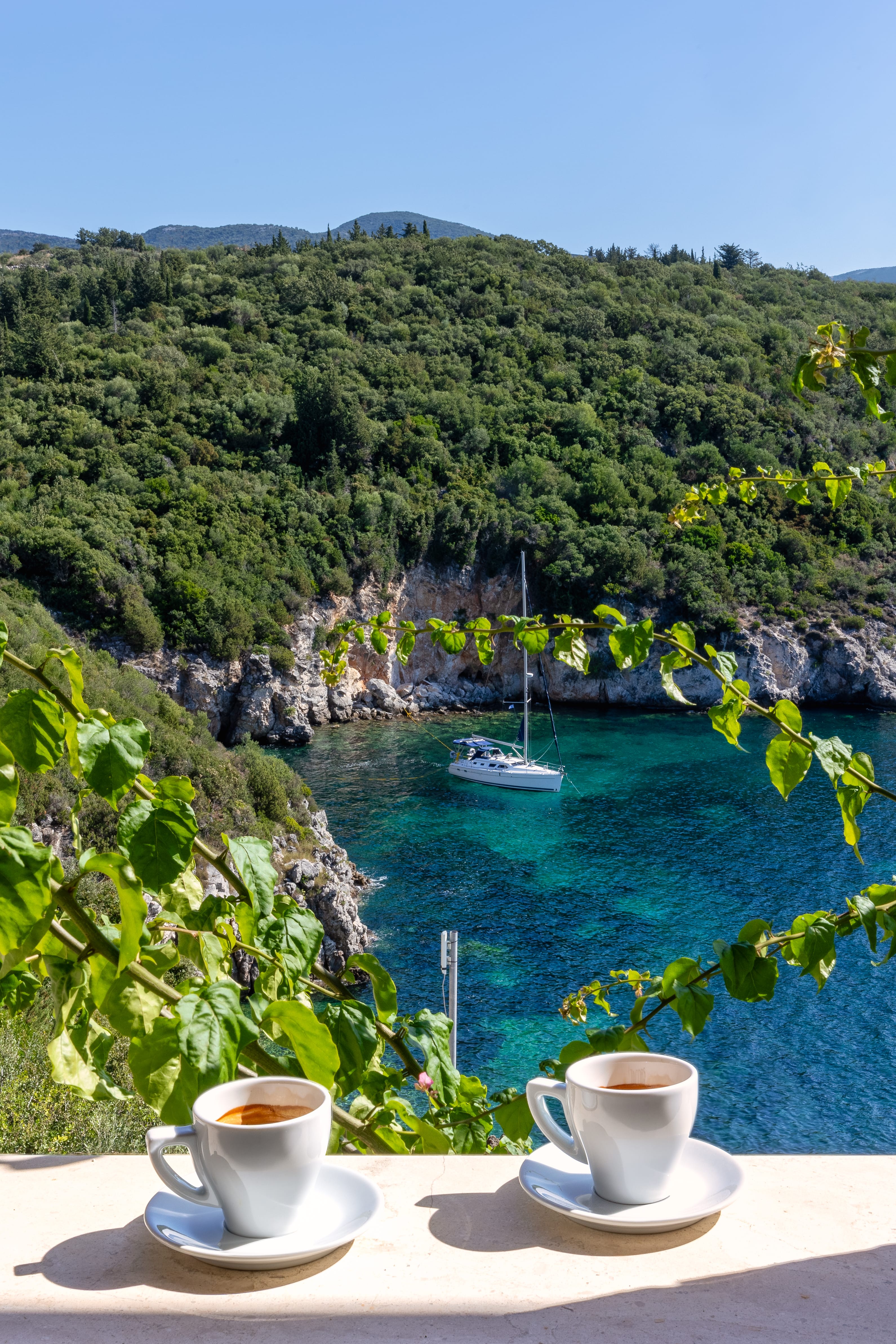 a cup of coffee on a table overlooking a body of water