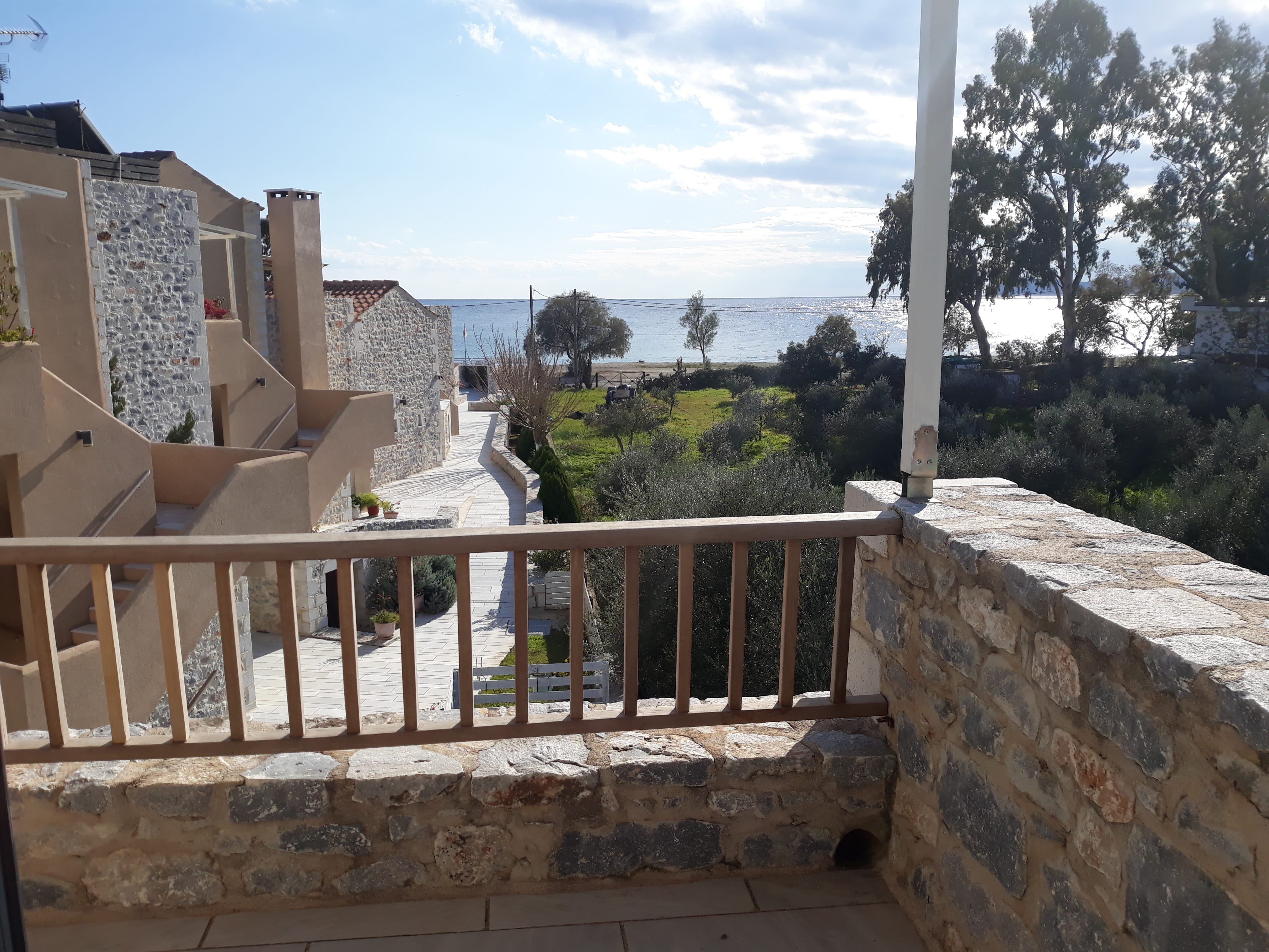 a stone wall with a railing and trees and a body of water in the background