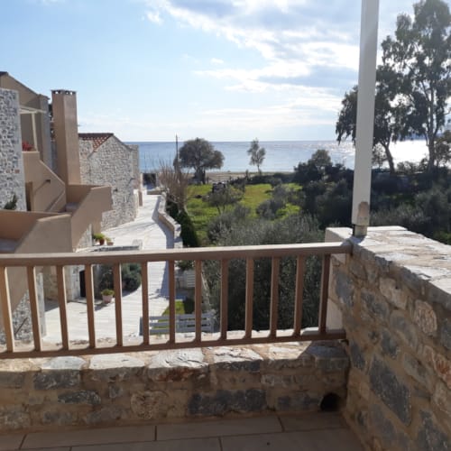a stone wall with a railing and trees and a body of water in the background