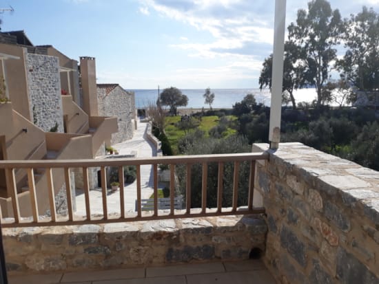 a stone wall with a railing and trees and a body of water in the background