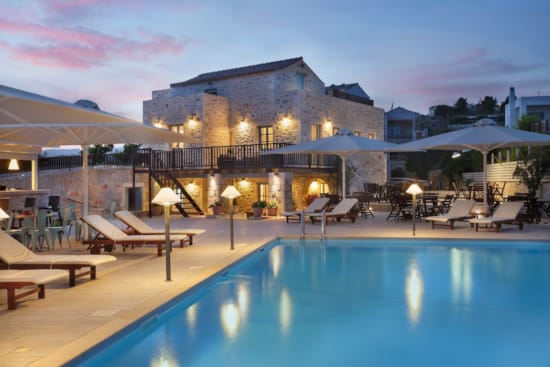 a pool with lounge chairs and umbrellas by a house