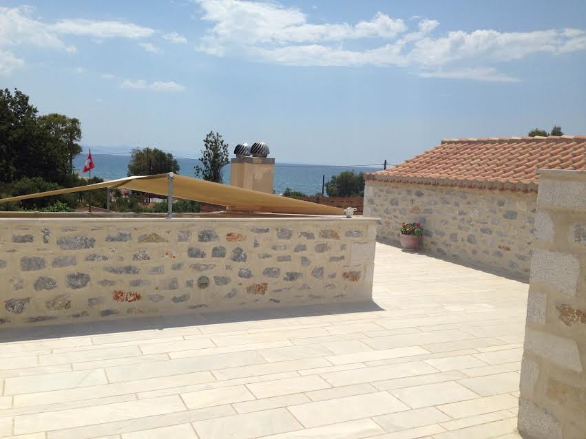 a stone patio with a stone wall and a body of water in the background