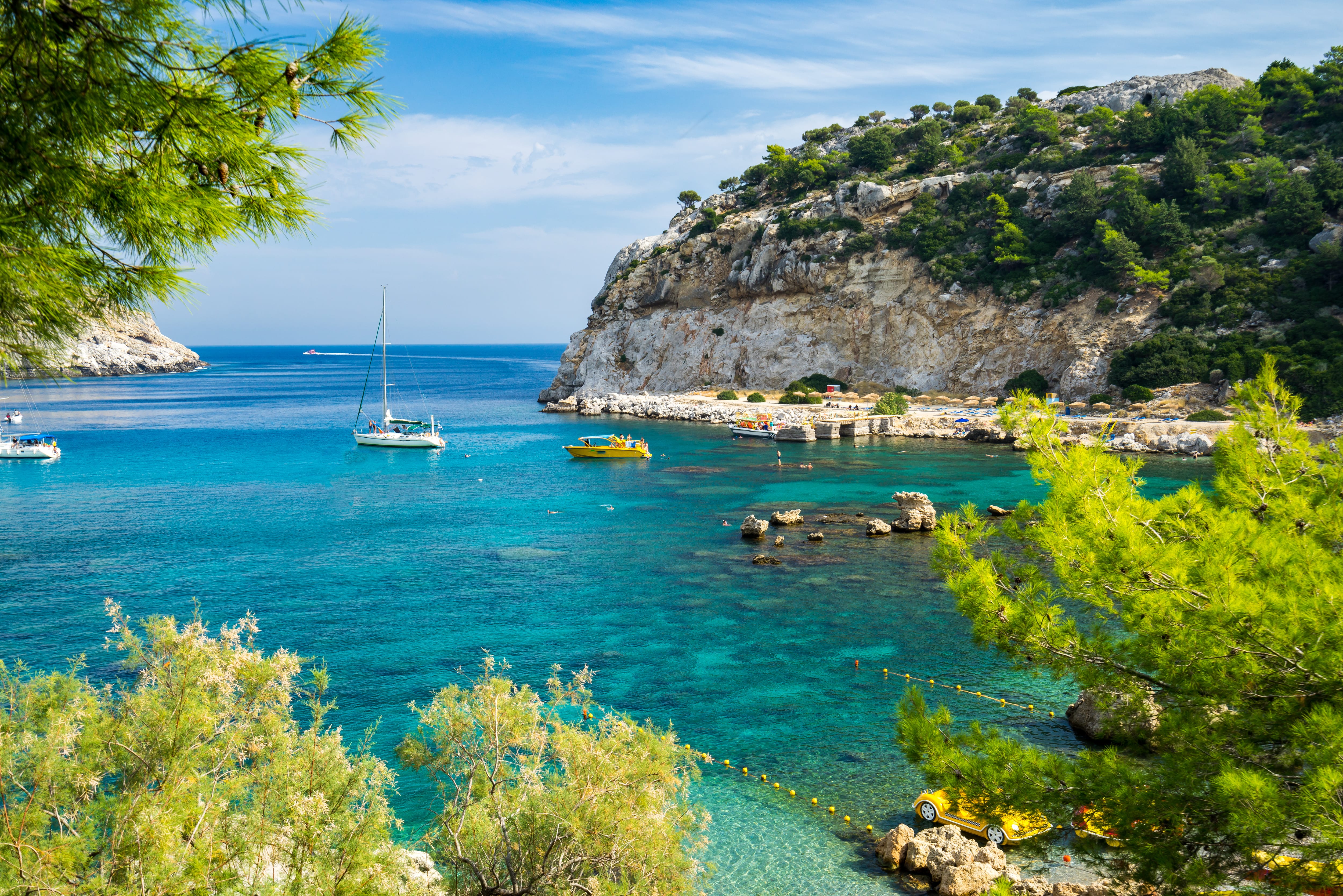 a body of water with boats and rocks by it