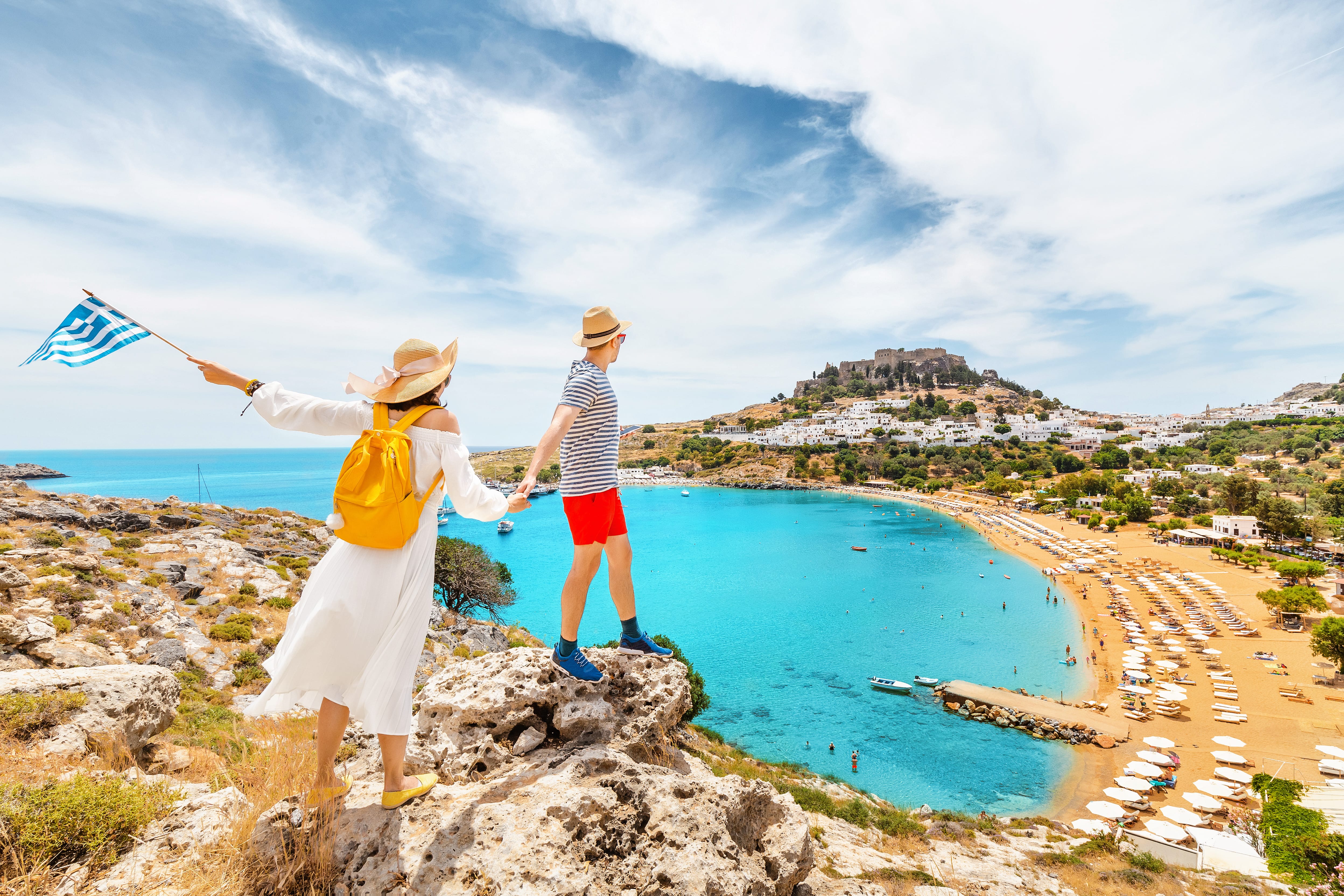 a couple of people holding flags on a cliff above a body of water
