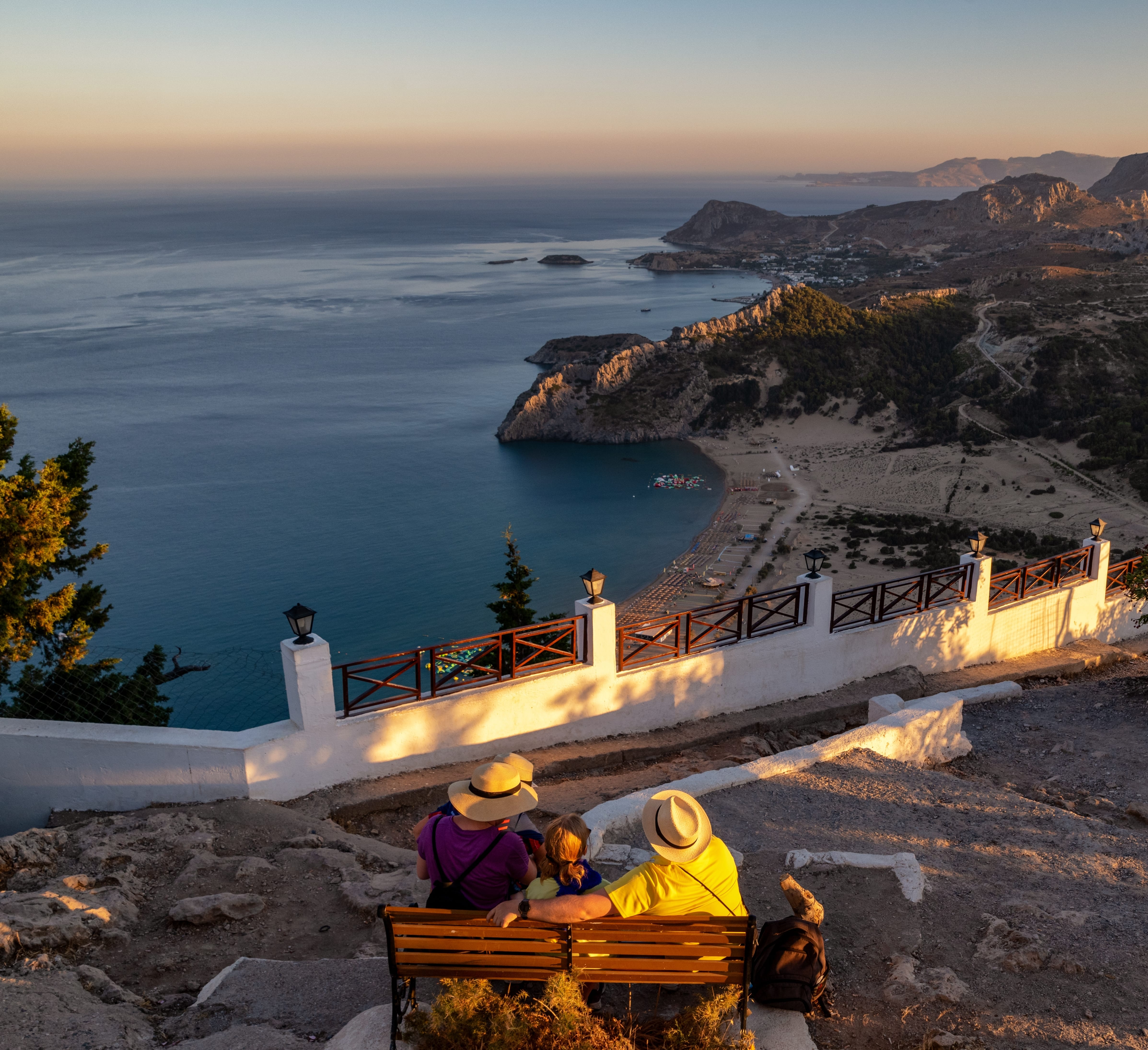 a group of people sitting on a bench overlooking a body of water