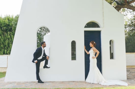 a man and woman in wedding attire walking out of a white building