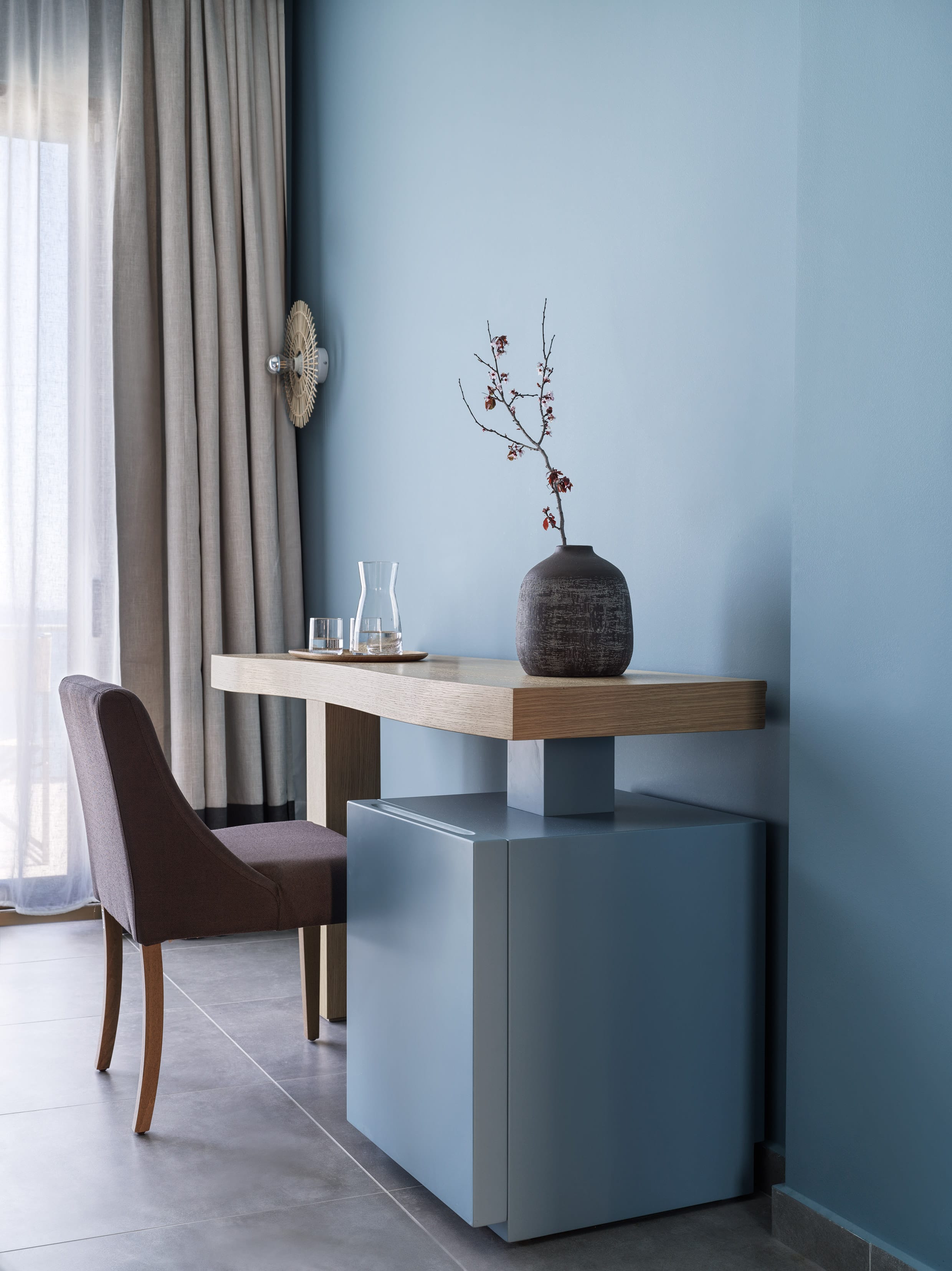 a desk with a chair and a vase on it