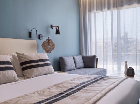 a bed with a chair and a table with a lamp on it