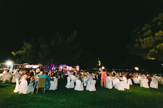 a group of people in white dresses and hats sitting on grass at night