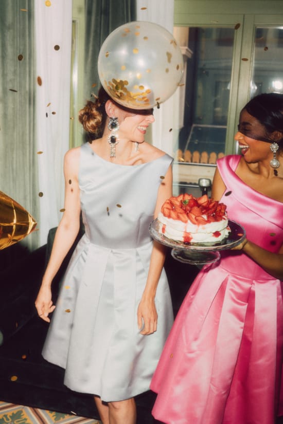 a person in a white dress holding a cake with a large hat