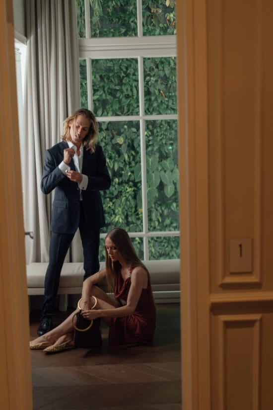 a woman sitting on the floor next to a man standing in a doorway