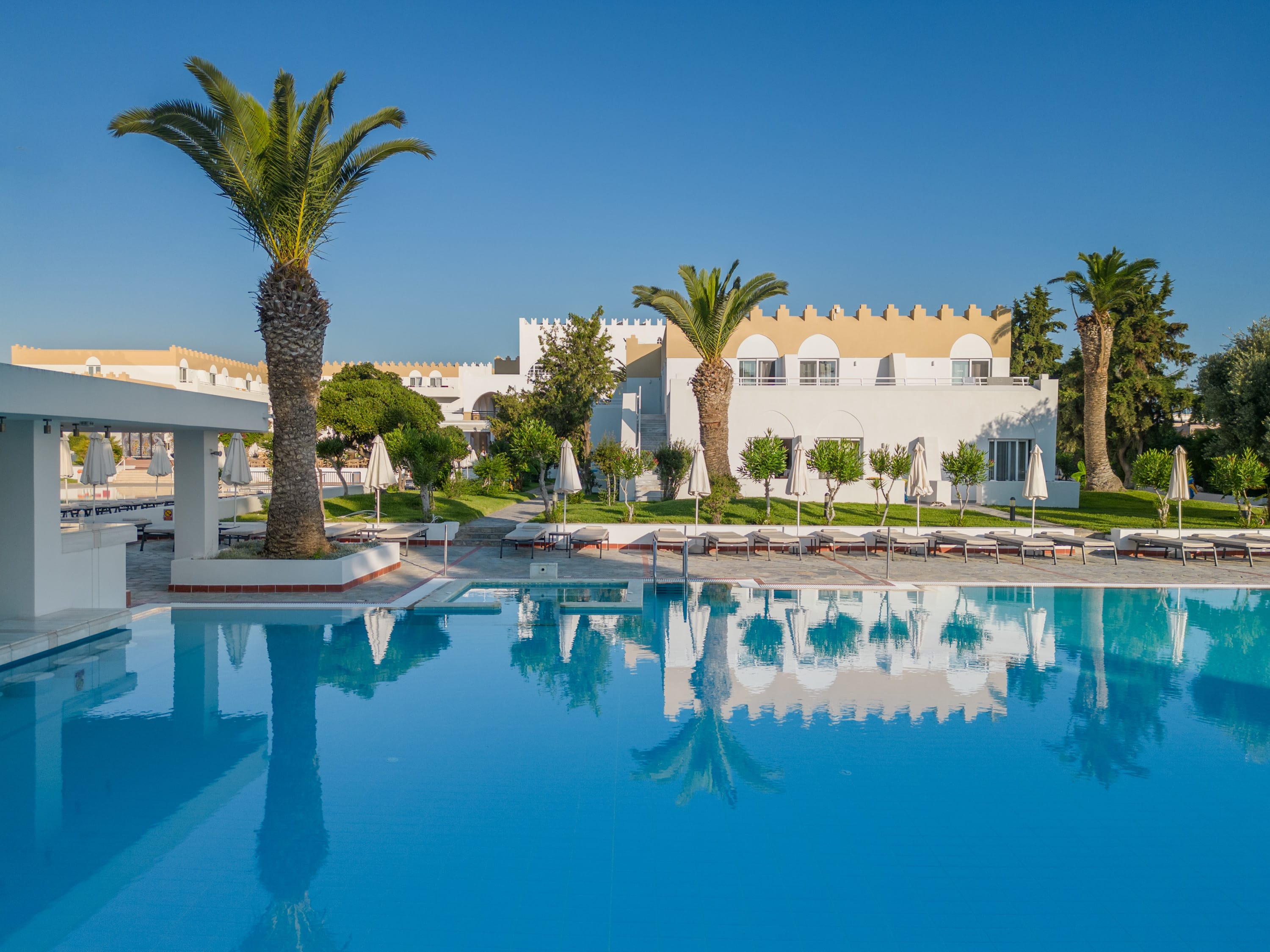 a pool with palm trees and a building in the background