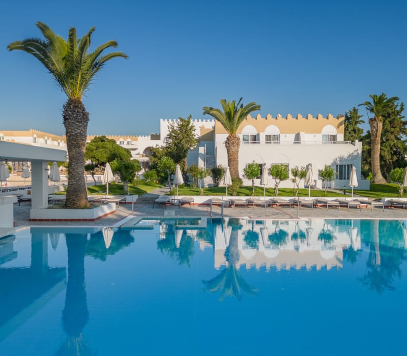 a pool with palm trees and a building in the background
