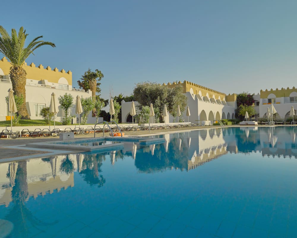 a pool with palm trees and buildings