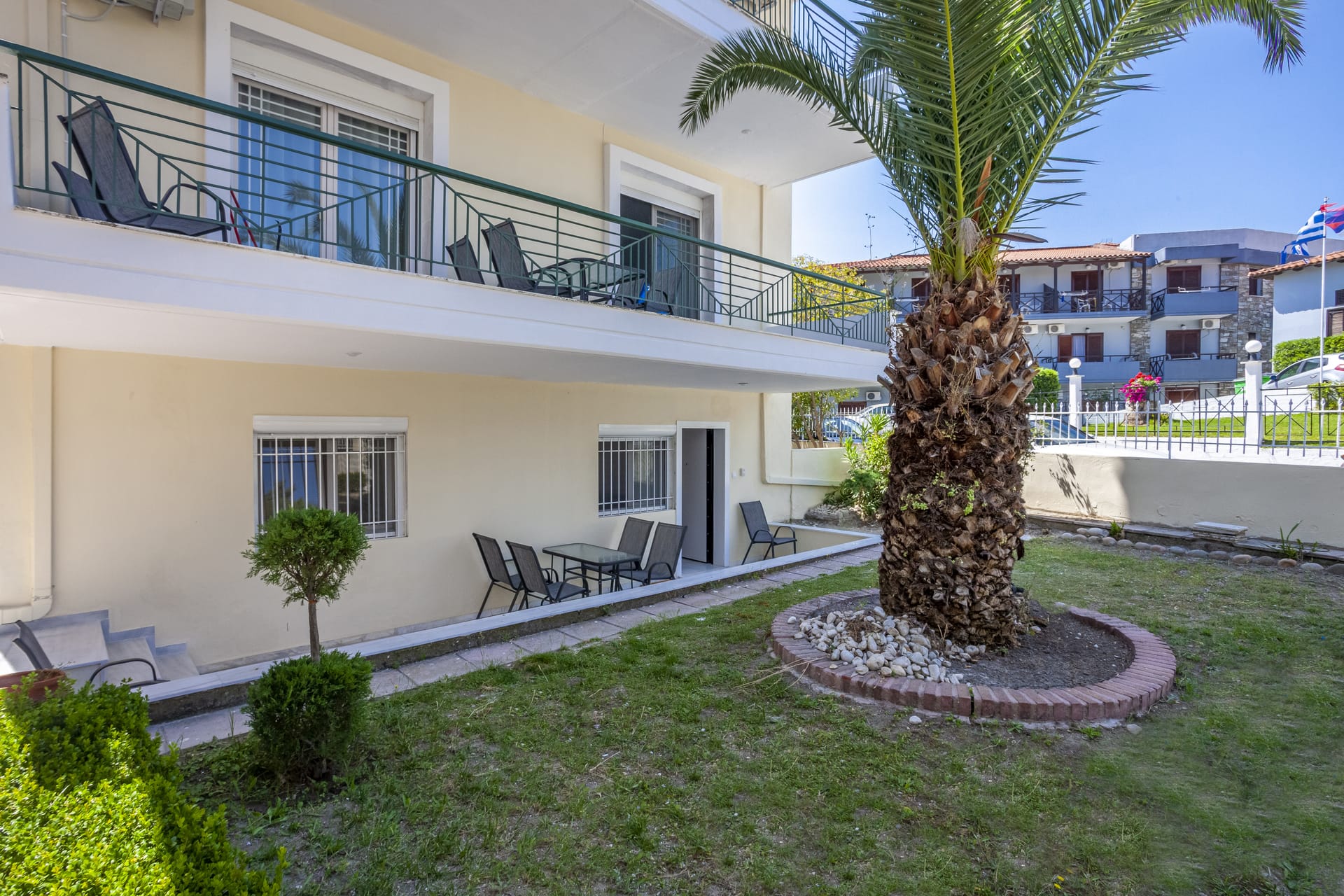 a courtyard with a palm tree and chairs and a building