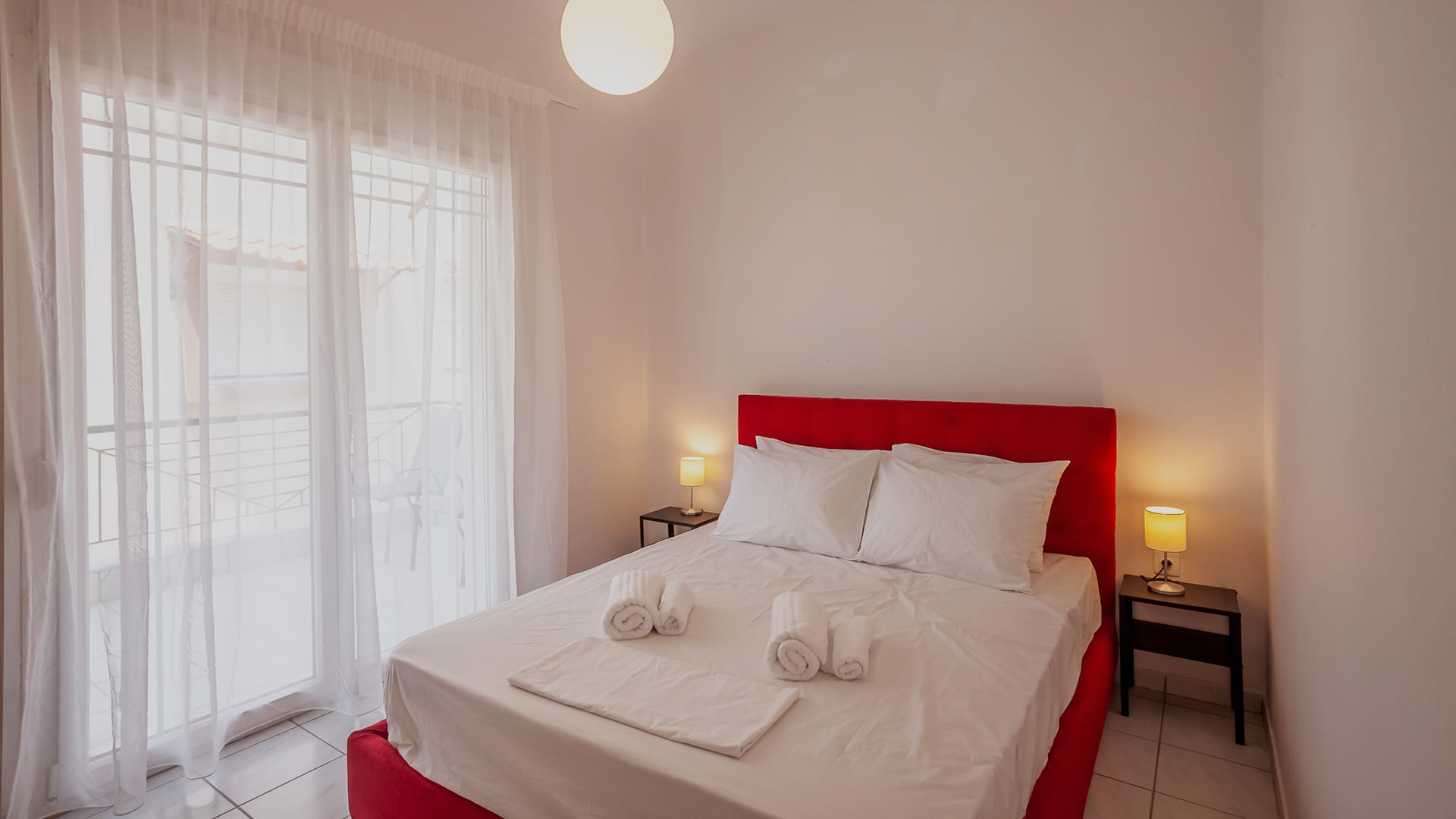 a bed with white sheets and red pillows
